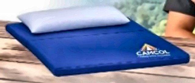 Colchoneta CAMCOL azul con almohada, sobre mesa de madera